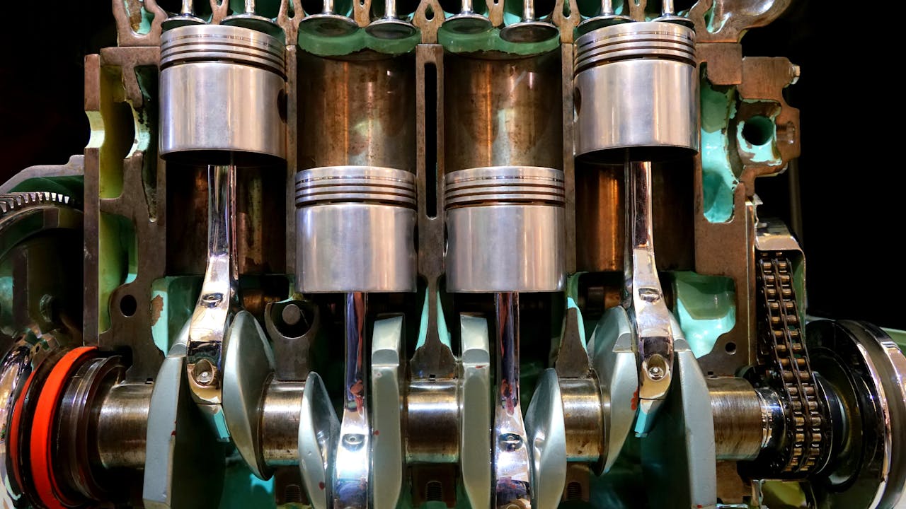 why-choose-us Close-up image of car engine pistons and crankshaft, showcasing mechanical components.