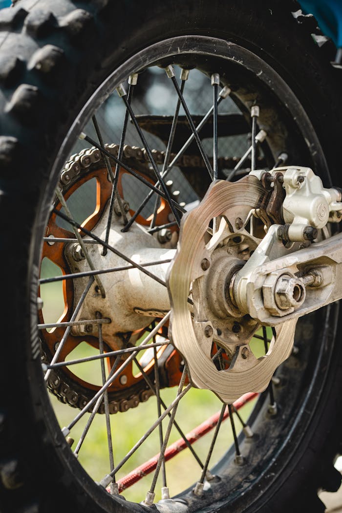 about-bg Detailed view of a dirt bike wheel showcasing the brake disc and tire in an outdoor setting.